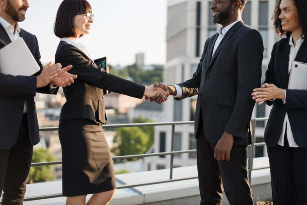 Profissionais cumprimentando-se durante uma reunião de negócios, representando uma etapa da jornada do cliente e o fortalecimento do relacionamento entre empresa e cliente.