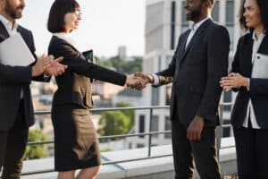 Profissionais cumprimentando-se durante uma reunião de negócios, representando uma etapa da jornada do cliente e o fortalecimento do relacionamento entre empresa e cliente.
