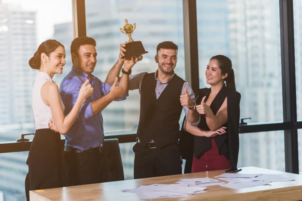 Equipe comemorando prêmio por incentivo por desempenho após atingir metas inteligentes no ambiente corporativo.
