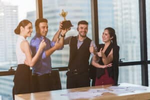 Equipe comemorando prêmio por incentivo por desempenho após atingir metas inteligentes no ambiente corporativo.