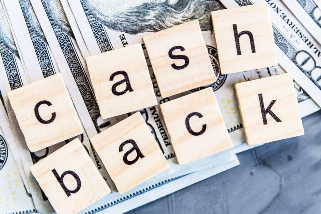 Palavra cashback formada por cubos de madeira sobre cédulas de dinheiro, representando cashback para empresas e fidelização de clientes.