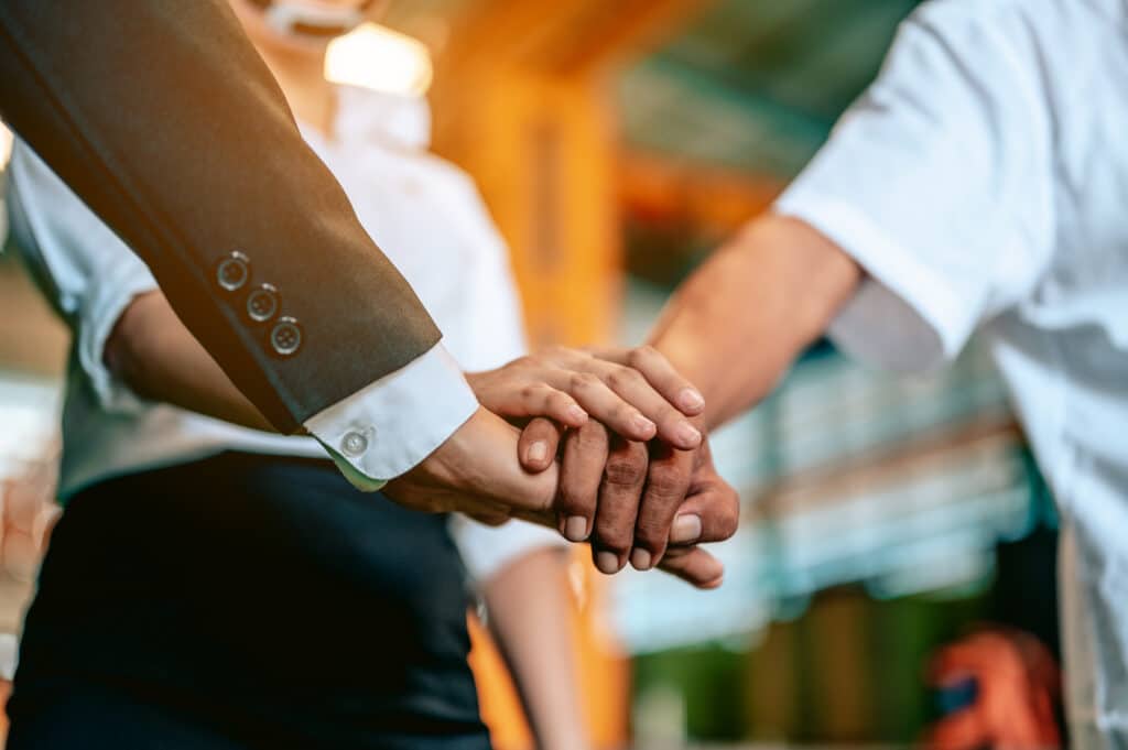 Equipe unindo as mãos em sinal de parceria e confiança, representando estratégias de Loyalty Marketing, fidelização e relacionamento com clientes.
