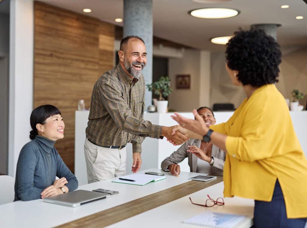 Equipe atendendo um cliente em ambiente corporativo, representando Customer Experience e experiência positiva do cliente.